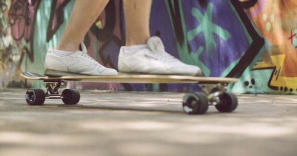 Feet Of a Man In Sneakers On Top Of Longboard alt