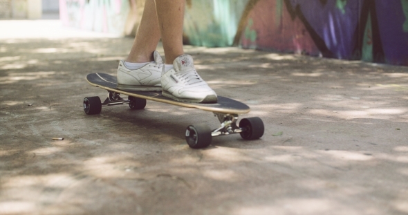 Feet Of a Man In Sneakers On Top Of Longboard Feet Of a Man In Sneakers On Top Of Longboard