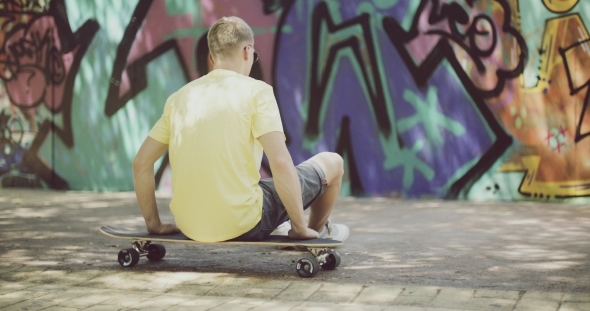 Man Sitting On Longboard And Looking Into Distance alt