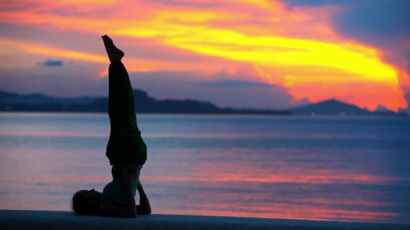 Young Woman Doing Yoga Exercise Over The Sunset