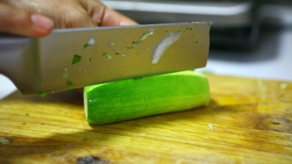 Female Hands Chopping Cucumber On a Wooden Board