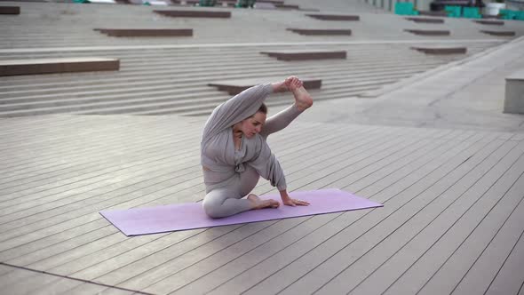 Front View of Professional Yoga Trainer Practicing Advanced Yoga Poses Sitting on Yoga Mat Outdoors alt