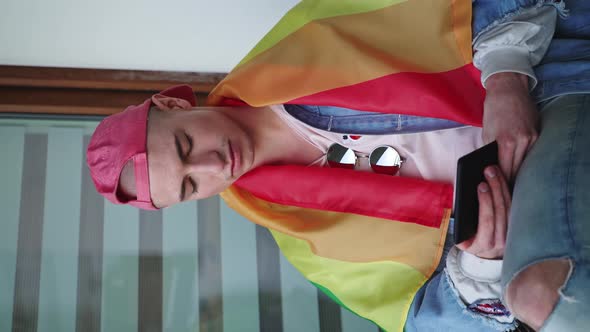 Vertical Shot of a Caucasian Gay Man with a Red Cup on His Bald Head and Rainbow Flag on His alt
