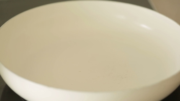 Hand Poured Oil In a White Frying Pan