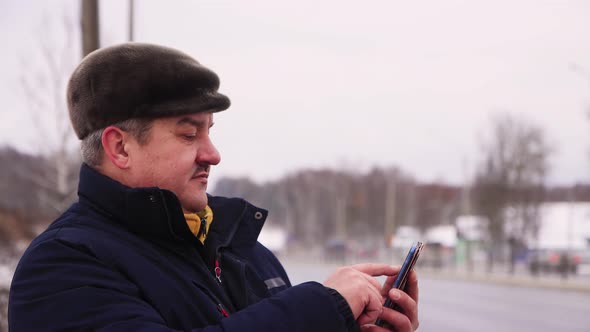 Business Man with a Mustache Makes a Message Online on a Smartphone alt