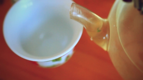 Pouring Green Tea In Cup From Teapot
