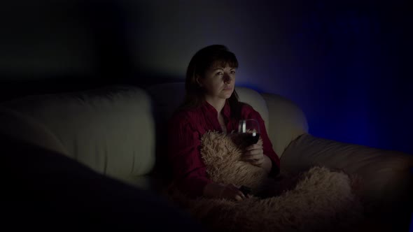 Woman Watches Tv in the Evening at Home with a Glass of Wine