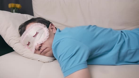 Man in a Sleep Mask Falls on the Sofa Exhausted Closeup alt