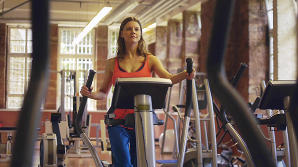 Young Woman Exercising On Elliptical Machine