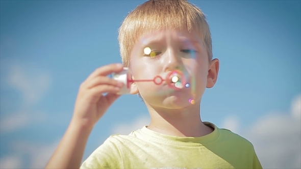Happy Little Boy Blowing Soap Bubbles alt