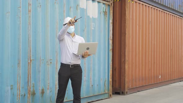 Logistic worker engineer man working in cargo container, wearing a face mask in warehouse alt