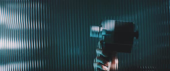 View through striped clear panel a vintage camera moving in blue lights alt