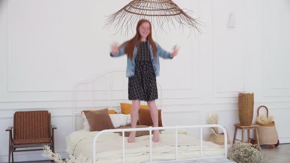 Happy Girl Having Fun and Jumping on White Bed