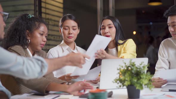 Asian young business people group have discussion meeting brainstorm overtime at night in office. alt