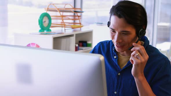 Male executive in headset working over computer at his desk 4k alt