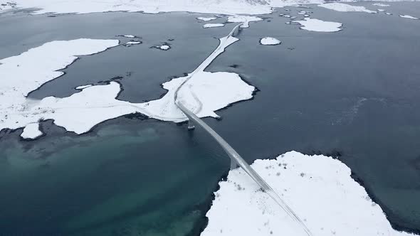 Drone footage of a car crossing a bridge in the Lofoten Islands, Norway. alt