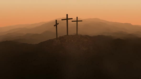 Atmospheric, dark image of three crosses silhouetted on the top of a mountain. alt