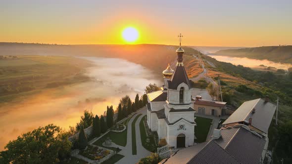 Aerial drone view of the Old Orhei at sunset. Valley with river and fog, monastery located on a hill alt