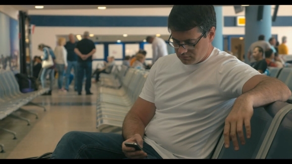 Young Man Using Cell Phone In Airport Lounge Young Man Using Cell Phone In Airport Lounge