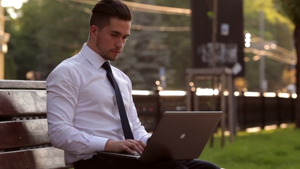 Young Man Working With a Laptop In Park Young Man Working With a Laptop In Park