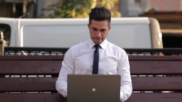 Young Man Working With a Laptop In Park Young Man Working With a Laptop In Park
