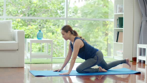 Young woman doing stretching workout on exercise mat at home