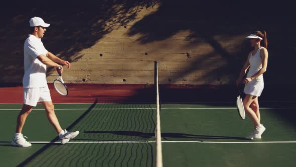 Woman and man playing tennis on a sunny day alt