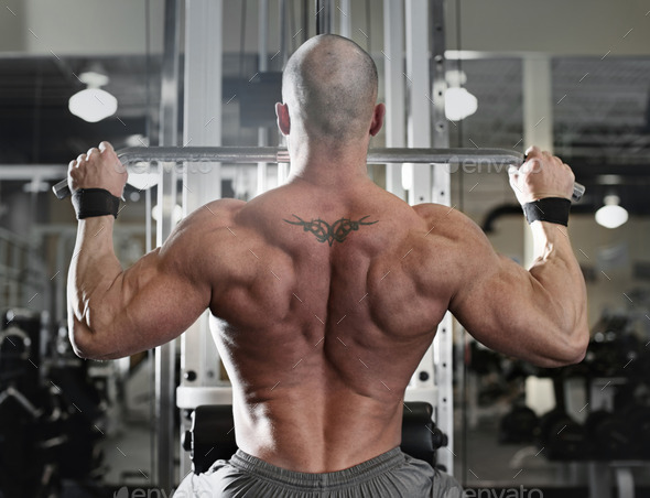 bodybuilder working out at the gym while using fitness machine - Stock Photo - Images