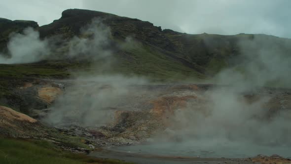 iceland landscape, geothermal hotspring steam smoke rising, distant figure of photographer taking a alt