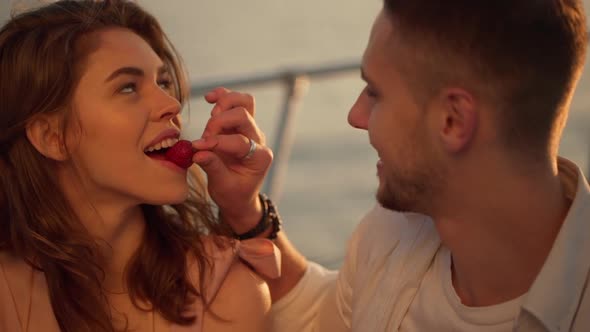 Handsome Guy Feeding Beautiful Attractive Longhaired Girl with Strawberry While Sailing on Yacht at alt