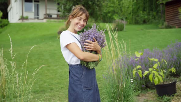 Live Camera Zoom in to Smiling Happy Gardener Posing with Bouquet of Lavender Outdoors alt