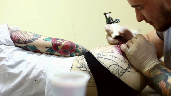 Tattoo Artist Creates Design On Woman's Hip
