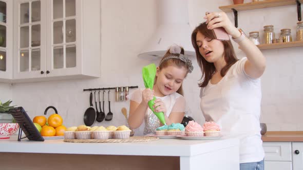 Mother and Daughter Icing Cupcakes and Having Video Call