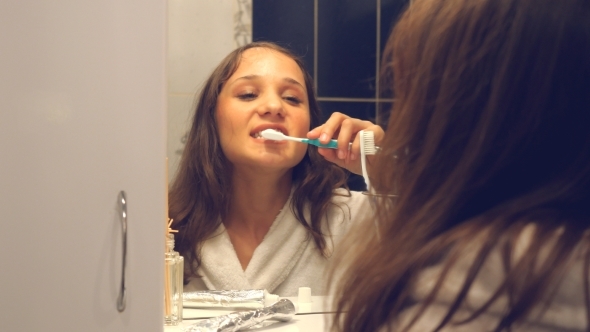 Young Pretty Woman Brushing Teeth In Front Of The