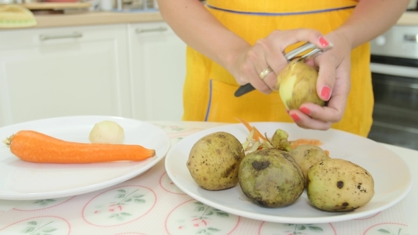 A Woman With Orange Manicure Peeling a Potatoes A Woman With Orange Manicure Peeling a Potatoes