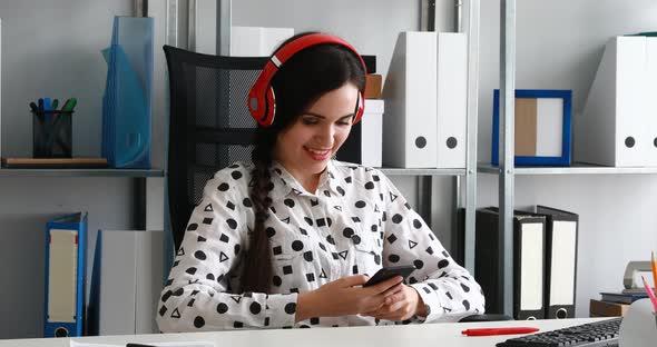 Businesswoman in Headphones Using Smartphone in Modern Office