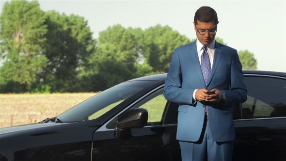 Young Businessman Calling On The Phone Next To Car Young Businessman Calling On The Phone Next To Car