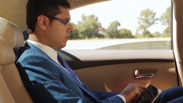 Businessman Sitting In The Car Reading Tablet Businessman Sitting In The Car Reading Tablet