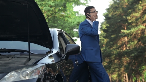 Businessman On a Mobile Phone Next To a Broken Car Businessman On a Mobile Phone Next To a Broken Car