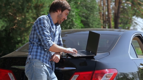 Man Working On The Computer In The Trunk Of Car Man Working On The Computer In The Trunk Of Car