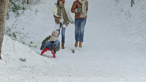 Parents Running After Son on Sled alt