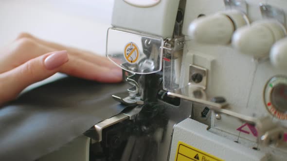 Closeup the Overstitching Machine Passes the Edges of the Black Fabric in Slow Motion alt