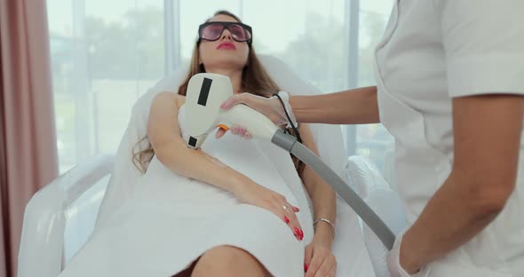 Beautician Removes Hair on Beautiful Female Hands Using a Laser alt