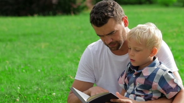 Father And Son Reading Book In Park Father And Son Reading Book In Park