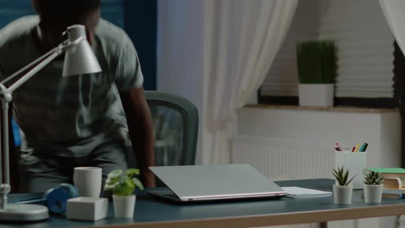 Business Man of African Ethnicity Sitting at Desk to Work on Laptop alt
