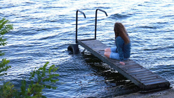 Girl Sitting on a Pier Looking at the Waves Girl Sitting on a Pier Looking at the Waves