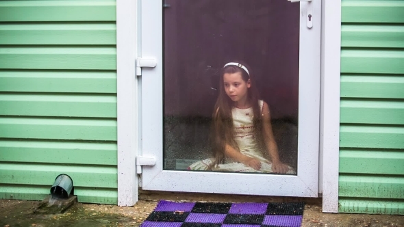 Sad Girl Sitting At Glass Door And Looking At Rain