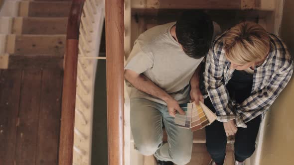 Adult couple looking at colour swatch on staircase in new home