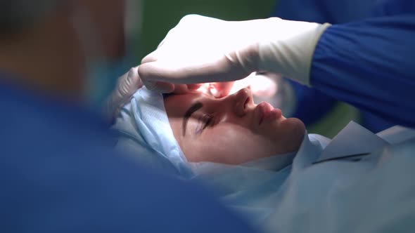 Closeup Side View Young Woman on Surgery Bed with Expert Doctor Cleaning Eyelid Dissection in Slow alt