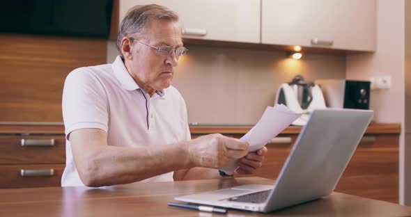 European Caucasian Confused and Uncertain Senior Man Paying Online Bills Using Laptop alt
